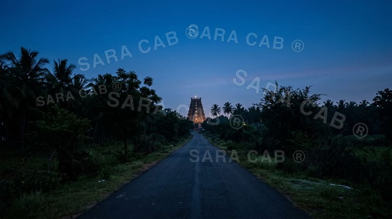 Pre-dawn road toward a distant lit temple gateway